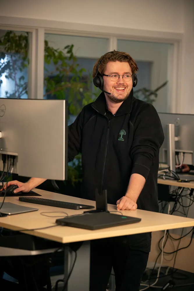 En medarbejder i Brugerservice med headset ved sit skrivebord.
